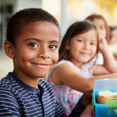 kids sitting at a school lunch table, smiling