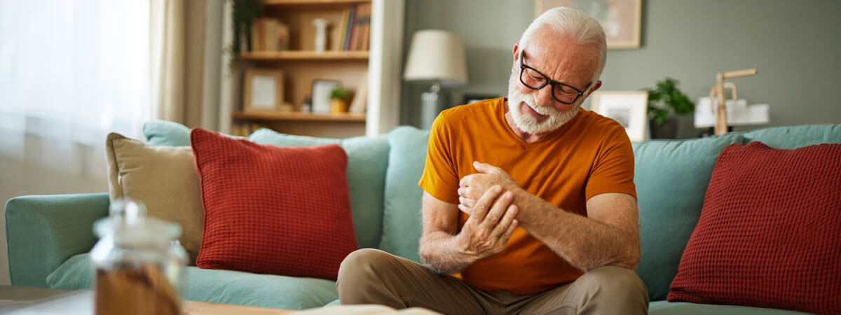 Senior man massaging painful hand joints at home