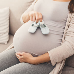 pregnant woman holding baby shoes