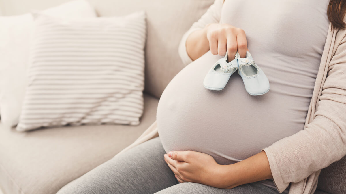 Pregnant mom holding shoes for a baby