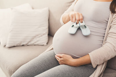 Pregnant woman with baby shoes