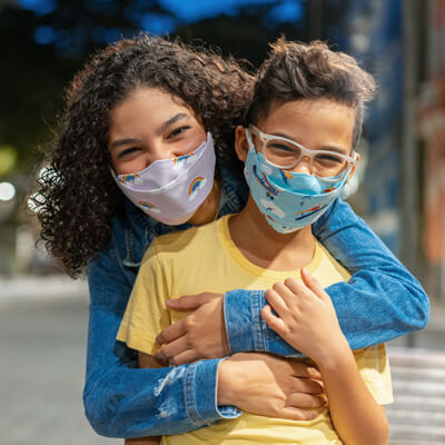 mom hugging young child while wearing masks