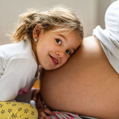 Little girl on moms pregnant belly