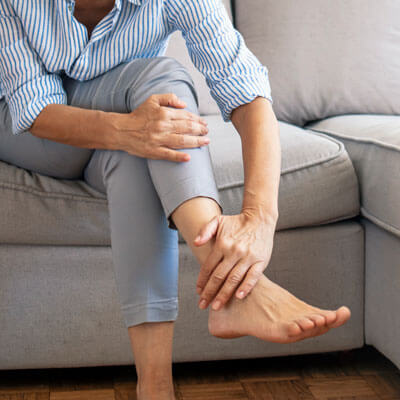 Woman sitting on couch holding foot