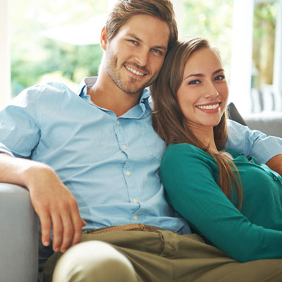 Young, happy couple sitting on couch smiling