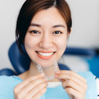 Woman holding clear aligners and smiling