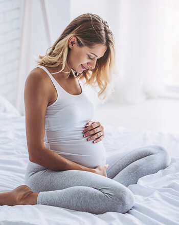Smiling pregnant woman looking at her stomach