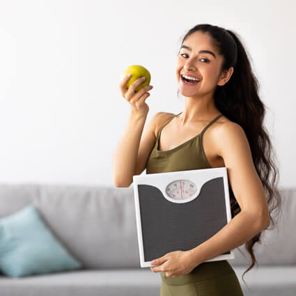 Woman holding a weight scale and an apple
