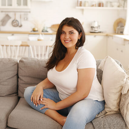 Smiling woman in white shirt sitting on sofa