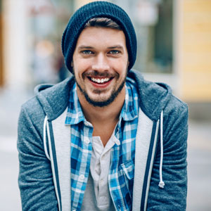 Young man smiling in jacket and hat