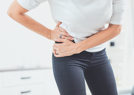 standing woman holding hip in pain
