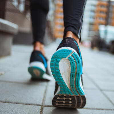 Close up of shoes while woman walks on tiled concrete