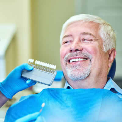 Teeth whitening chart next to man's teeth