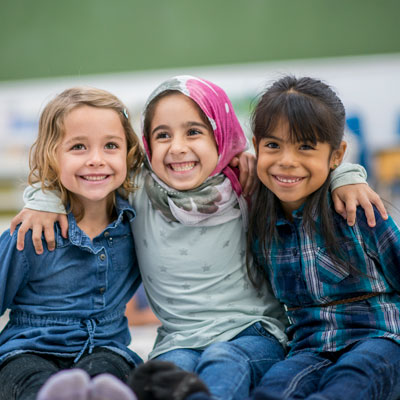 Three young girls hugging and smiling