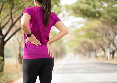 woman standing outdoors holding side in pain