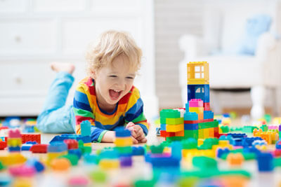 toddler boy laying on the floor playing with building blocks