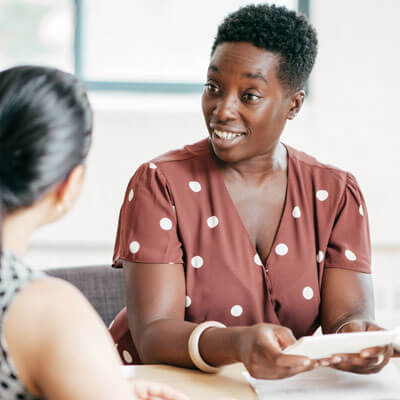 two women talking and going over paperwork