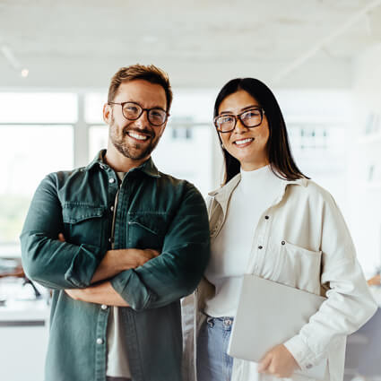 man and woman smiling and standing in an office
