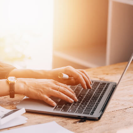 Typing on laptop in sunlight