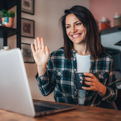 A woman drinking coffee while on a video call.