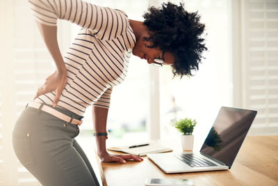 Woman at computer experiencing low back pain