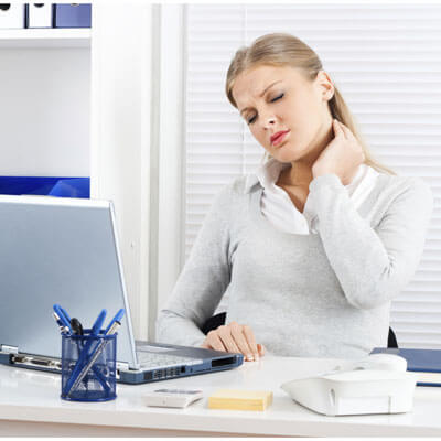Woman sitting at desk rubbing her neck