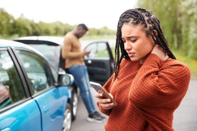woman checking phone after car accident