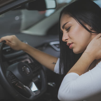 woman with neck pain sitting in her car