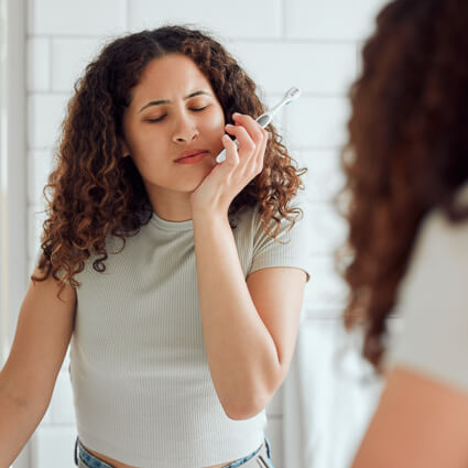 woman brushing teeth with tooth pain