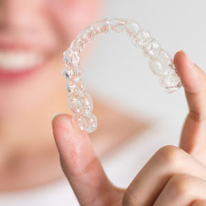 woman holding up a clear aligner