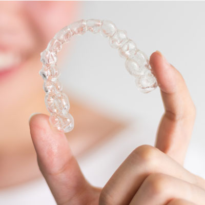 A woman holding clear aligners