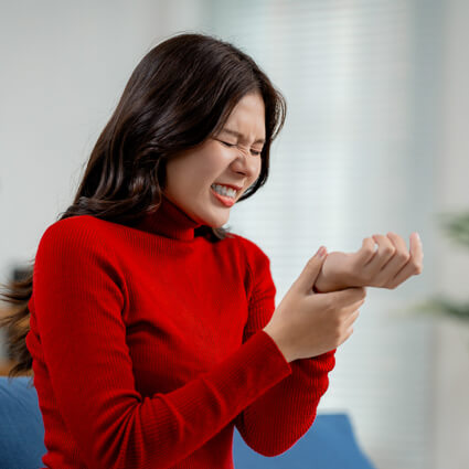 Woman in bright red shirt with wrist pain