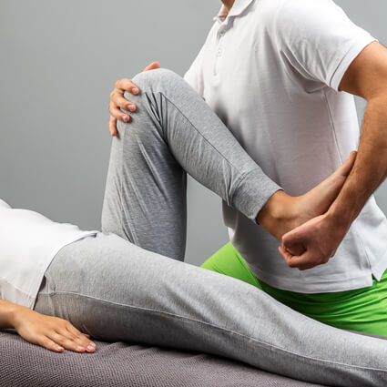 woman stretching knee with therapists help