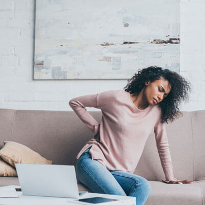 Woman leaning on sofa with back pain