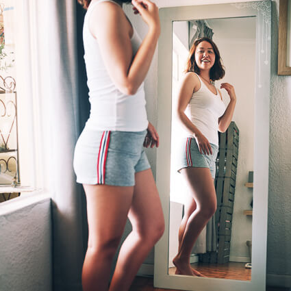 smiling woman looking at herself in a mirror