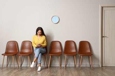Woman in yellow shirt waiting and looking at phone