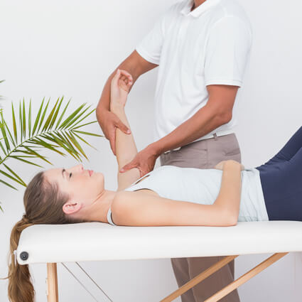 Woman lying on a table having her elbow adjusted