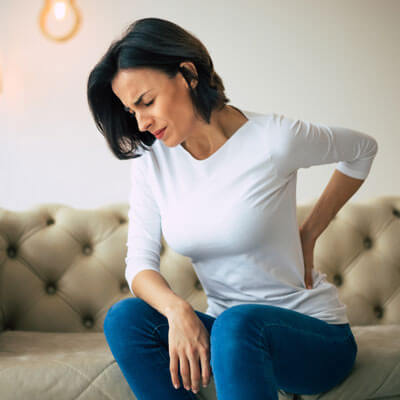 woman sitting on couch with pain on her back