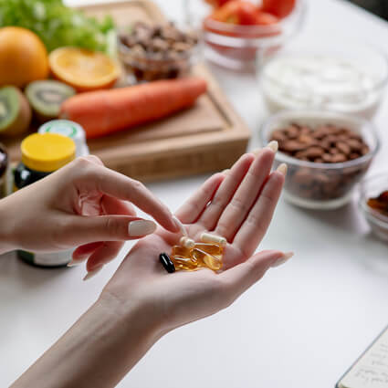 person with supplements in hand and healthy food in the background