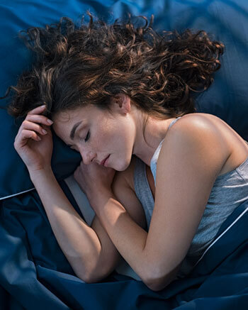 woman sleeping in cozy blue bedding