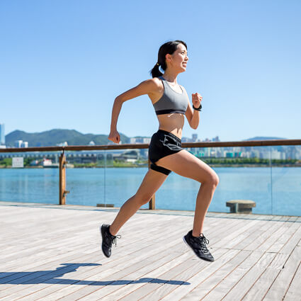 Woman sprinting down pier along water