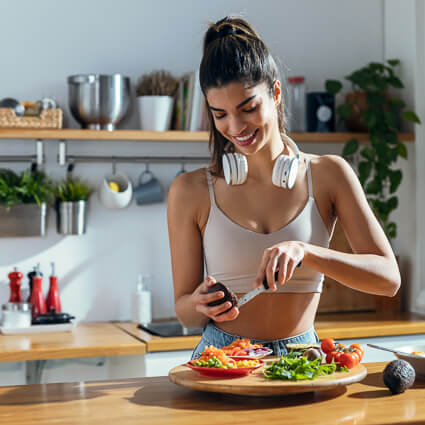 Woman standing in kitchen preparing plate of healthy food