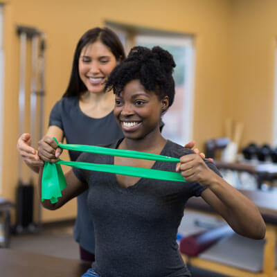 trainer and woman with strengthening band