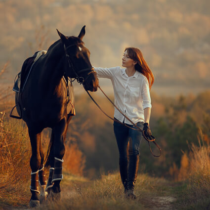 Woman walking a horse on a farm