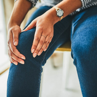 woman wearing jeans and holding knee in pain