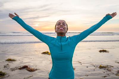 woman with arms out at beach