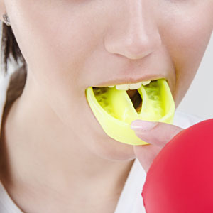 woman taking custom mouth guard out of mouth