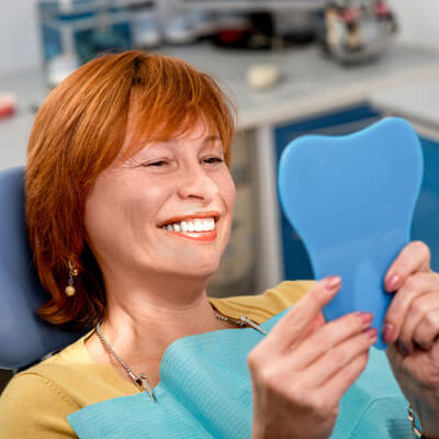 smiling person looking in hand mirror