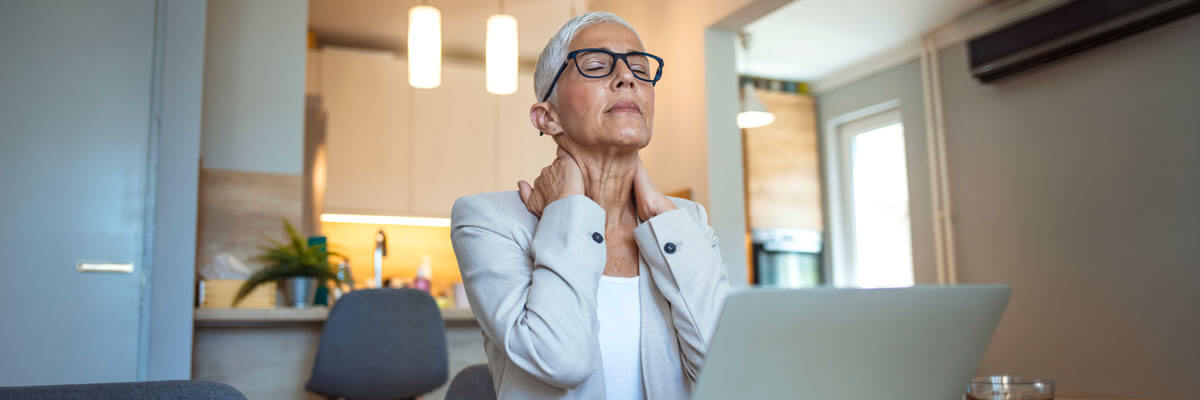 woman on computer holding neck in pain