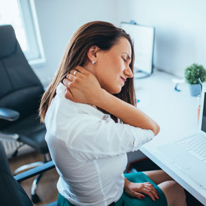 woman with neck pain sitting at work desk